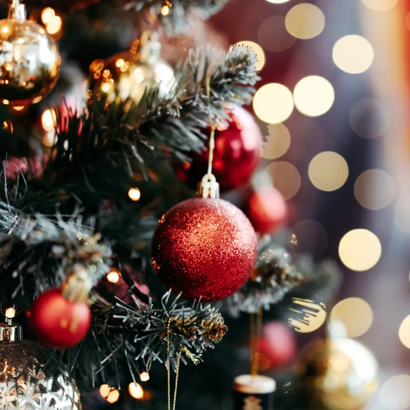 Decorated Christmas tree with red and gold ornaments and warm bokeh lights
