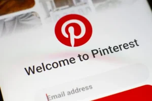 Person browsing Pinterest on a smartphone at a desk