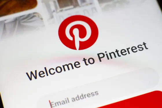 Person browsing Pinterest on a smartphone at a desk